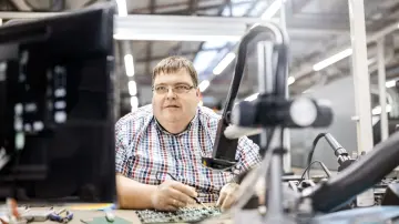 merkur-group-working-environment-production-employee-inspecting-electronic-components-microscope